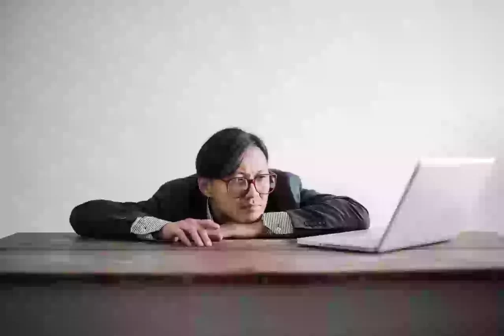 Person with glasses looking tired at laptop
